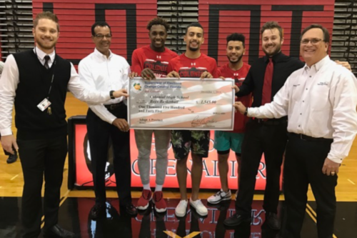 Basketball plays holding an oversized check.