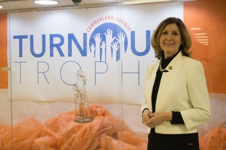 The County Clerk in front of the trophy and its display case.