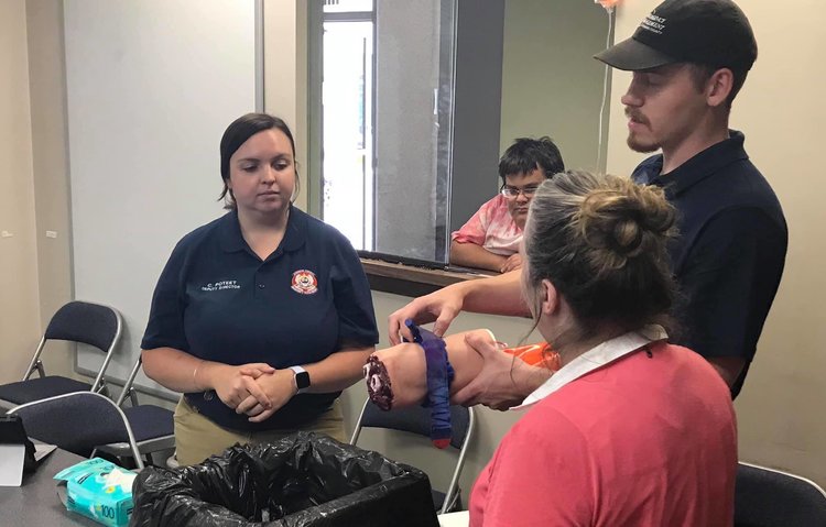 Emergency management experts showing how to stop bleeding using props.