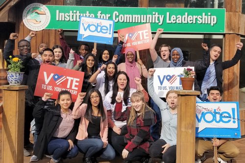 A young, diverse group of people holding "vote" signs.
