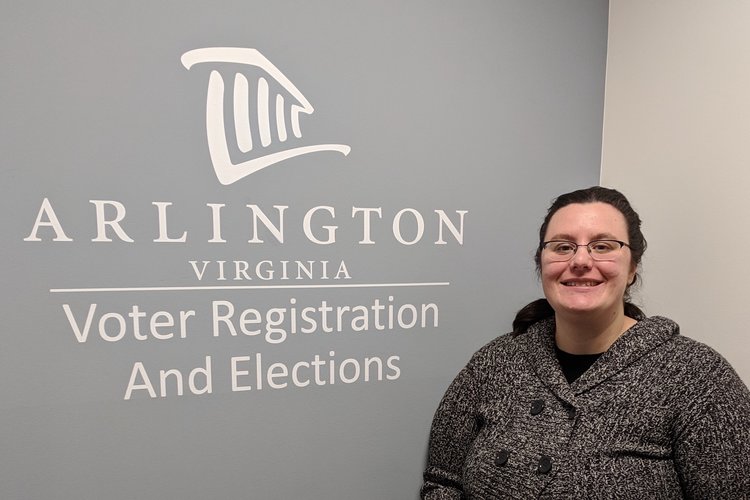 Gretchen standing in front of the Arlington Elections logo.