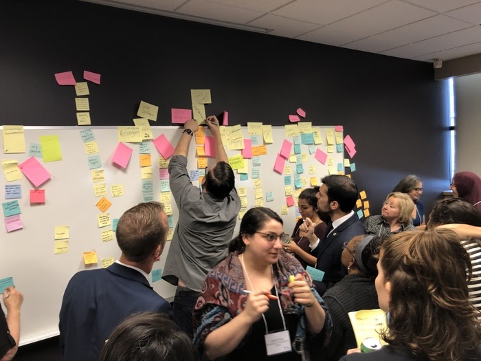 Workshop attendees put colorful sticky notes on the wall