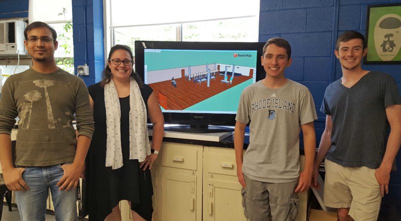 Professor Macht with three young students in front of a screen showing a simulation to reduce voter wait times