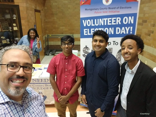 Students pose in front of a billboard that says "Volunteer on Election Day!"