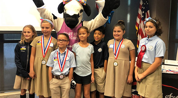 Children pose for a photo wearing their medals and ribbons.