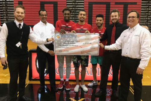 Basketball players and election officials hold a large check