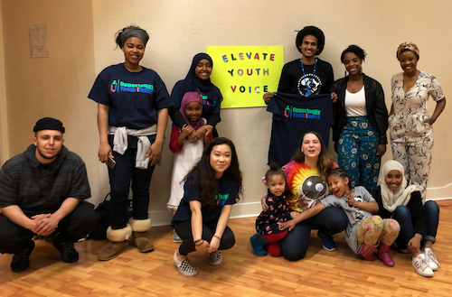 A group of young adults poses for a photo with a sign that says "Elevate Youth Voice."