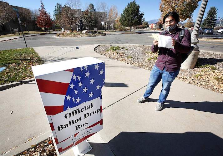 A college student prepares to place his ballot in a drop box on campus.