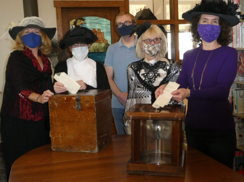 four people pose with old wooden ballot boxes