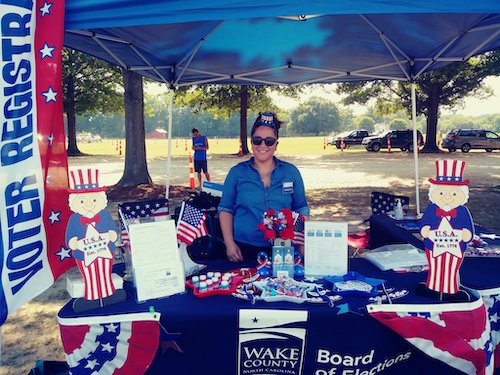 A person stands at a booth decorated for the 4th of July.